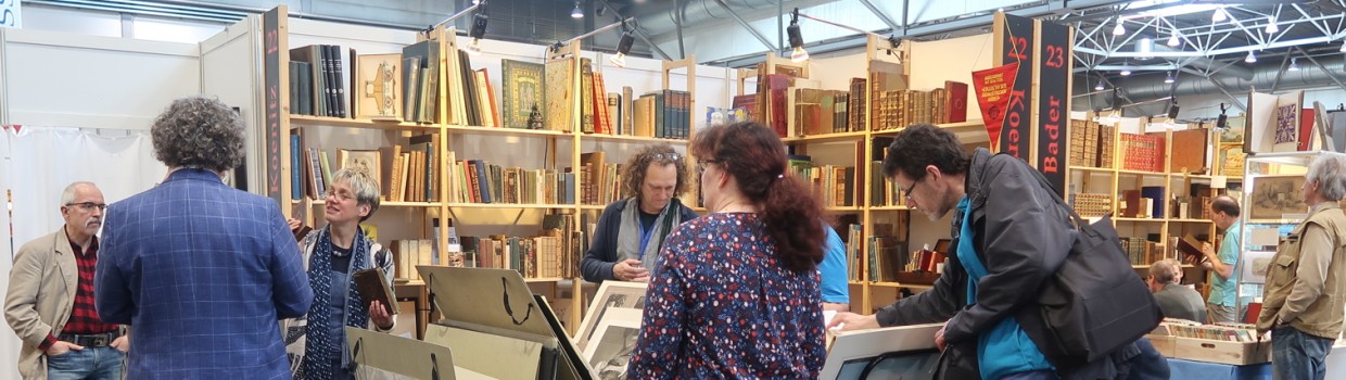Leipziger Antiquariatsmesse: Besucher:innen stöbern in Antiquariaten vor gefüllten Bücherregalen