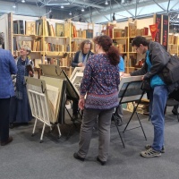 Leipziger Antiquariatsmesse: Besucher:innen stöbern in Antiquariaten vor gefüllten Bücherregalen