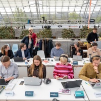 an langen Tischen sitzen Podcaster:innen auf der Leipziger Buchmesse 2023 und arbeiten an ihren Laptops