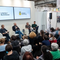 Foto vom vollbesetzten Medienforumauf der Leipziger Buchmesse 2023 bei einem Talk mit 4 Personen