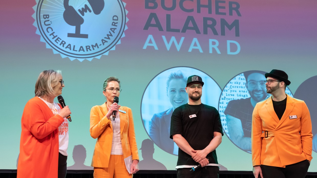 4 Personen, u.a. Lena Stenz und Kerstin Krämer von der Leipziger Buchmesse, stehen auf der Bühne und präsentieren den Bücheralarm Award 2023