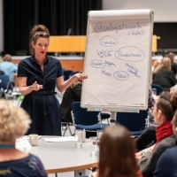 Tischpräsentation einer Rednerin am Flipchart im vollen Saal der Leipziger Autor:innenrunde 2024