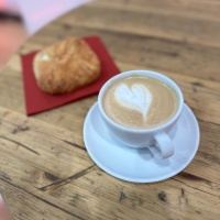 Kaffeetasse und Croissant auf einem Holztisch in der buchbar während der Leipziger Buchmesse 2024