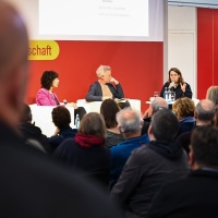 Bühnengespräch mit 3 Teilnehmer:innen auf der Bühne des Forum Offene Gesellschaft vor vollbesetztem Publikum auf der Leipziger Buchmesse 2024