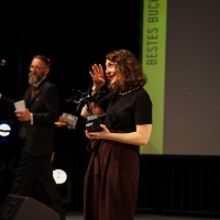 Die Preisträgerin Carina Schnell mit ihrem Preis auf der Bühne bei der Verleihung vom Seraph 2024 auf der Leipziger Buchmesse Die Preisträgerin Carina Schnell mit ihrem Preis auf der Bühne bei der Verleihung vom Seraph 2024 auf der Leipziger Buchmesse