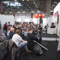 Bühnengespräch mit 2 Teilnehmer:innen auf der Bühne vom Medienforum vor vollbesetztem Publikum auf der Leipziger Buchmesse 2024
