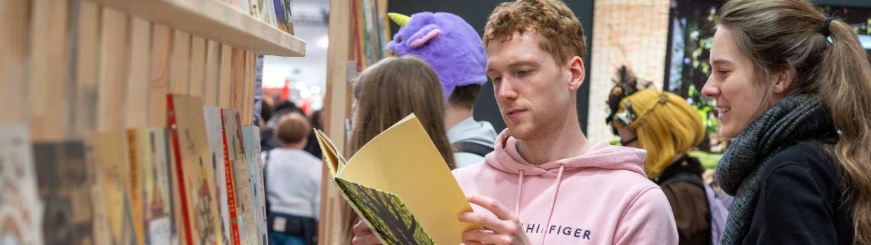 Ein Mann und eine Frau blättern in einem Bilderbuch auf der Leipziger Buchmesse 2024
