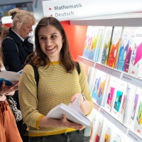 Lesende Besucherin an einem Messestand mit großem Bücherregal auf der Leipziger Buchmesse 2024