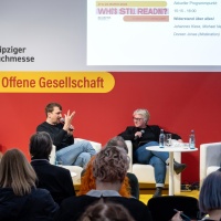 Bühnengespräch mit 3 Teilnehmer:innen auf der Bühne des Forum Offene Gesellschaft vor vollbesetztem Publikum auf der Leipziger Buchmesse 2024