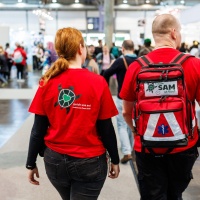 2 Personen vom Awareness Team SAM der Leipziger Buchmesse 2025 laufen durch die Messehalle