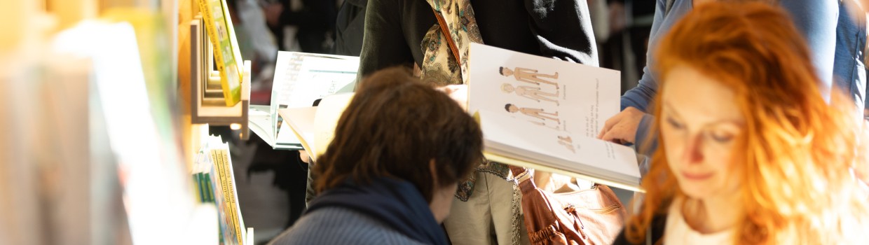 Impression von lesenden Besucher:innen an Bücherregalen auf der Leipziger Buchmesse 2025