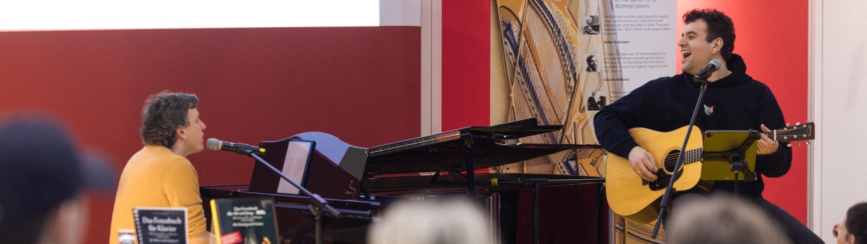 Das Musik-Café der Leipziger Buchmesse 2025 mit einer Bühnenveranstaltung von zwei Musikern an Gitarre und Klavierflügel vor vollbesetztem Publikum Das Musik-Café der Leipziger Buchmesse 2025 mit einer Bühnenveranstaltung von zwei Musikern an Gitarre und Klavierflügel vor vollbesetztem Publikum