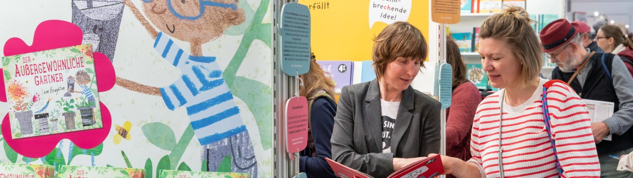 Zwei Frauen unterhalten sich über ein Kinderbuch auf der Leipziger Buchmesse 2025