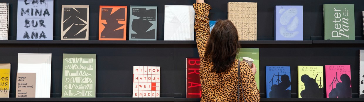 Besucherin der Leipziger Buchmesse 2025 nimmt ein Buch aus einer Wand mit ausgestellten Büchern Besucherin der Leipziger Buchmesse 2025 nimmt ein Buch aus einer Wand mit ausgestellten Büchern