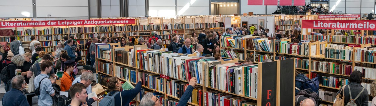 Leipziger Antiquariatsmesse auf der Leipziger Buchmesse 2025 mit Besucherinnen vor Bücherregalen