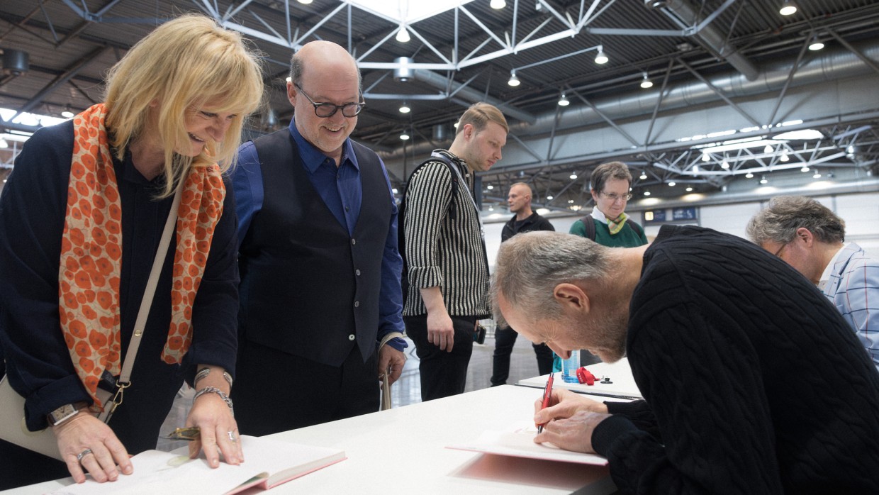 Autor signiert ein Buch für erfreute Fans an einem Signiertisch im Signierbereich der Leipziger Buchmesse 2025 Autor signiert ein Buch für erfreute Fans an einem Signiertisch im Signierbereich der Leipziger Buchmesse 2025