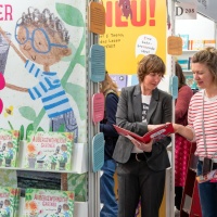 Zwei Frauen unterhalten sich über ein Kinderbuch auf der Leipziger Buchmesse 2025