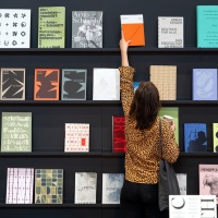 Besucherin der Leipziger Buchmesse 2025 nimmt ein Buch aus einer Wand mit ausgestellten Büchern