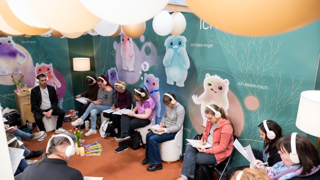 mehrere junge Erwachsene sitzen in einem Raum mit Kopfhörern auf der Leipziger Buchmesse 2026