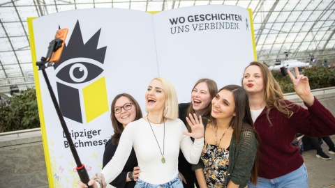 Fünf junge Besucherinnen machen ein Selfie vor der Buchmesse-Fotowand auf der Leipziger Buchmesse 2026