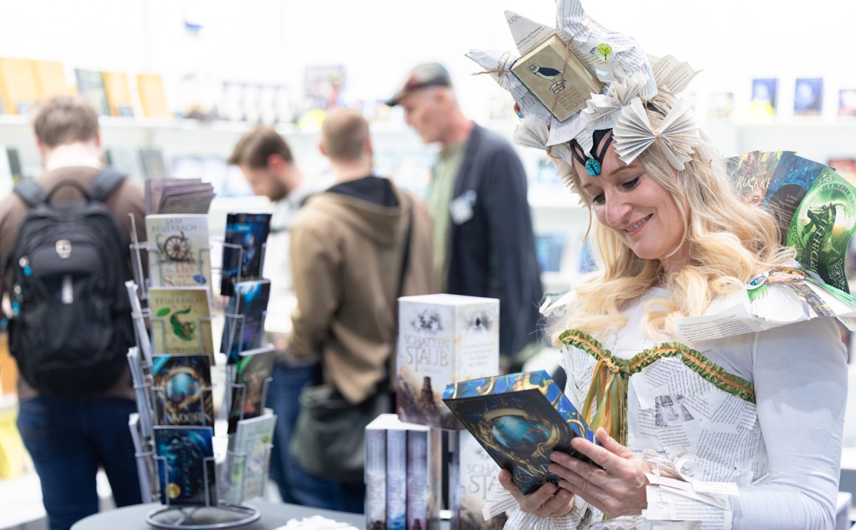kostümierte Person liest ein Buch im Phantastikbereich auf der Leipziger Buchmesse 2026