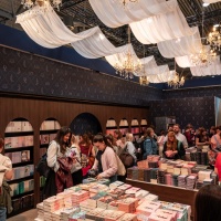 Besuchende stöbern an einem Buchstand unter Kronleuchtern auf der Leipziger Buchmesse 2026