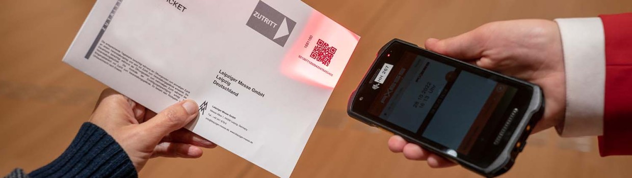 Eine Person lässt ihr Online-Ticket mit einem Handscanner prüfen.
