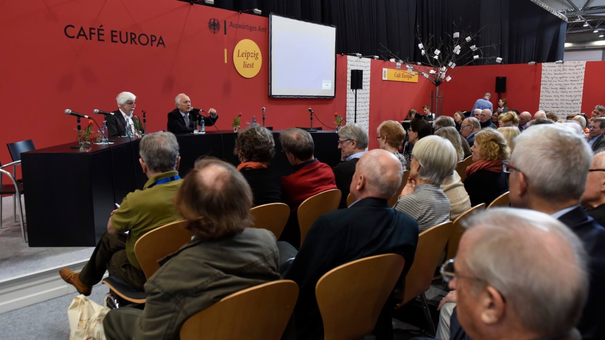 Eine Veranstaltung auf der Leipziger Buchmesse. Zwei Männer sitzen auf der Bühne an einem schwarzen Tisch, ihnen gegenüber das Publikum. Es handelt sich um das Café Europa. Eine Veranstaltung auf der Leipziger Buchmesse. Zwei Männer sitzen auf der Bühne an einem schwarzen Tisch, ihnen gegenüber das Publikum. Es handelt sich um das Café Europa.
