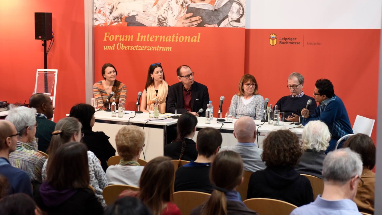 Eine Veranstaltung auf der Leipziger Buchmesse. An dem Tisch auf der Bühne sitzen 6 Personen, ihnen gegenüber das Publikum.