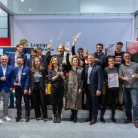 Menschen stehen aufgereiht vor eine Bühne um ein Foto zu machen. Manche von Ihnen halten einen Preis oder eine Urkunde hoch. Menschen stehen aufgereiht vor eine Bühne um ein Foto zu machen. Manche von Ihnen halten einen Preis oder eine Urkunde hoch.
