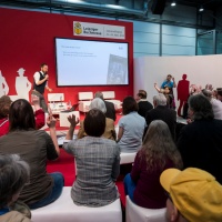 Eine Veranstaltung auf der Buchmesse. Ein Mann auf der Bühne spricht ins Mikrofon, ihm gegenüber sitzen Zuschauer:innen und heben teilweise die Hand.  Eine Veranstaltung auf der Buchmesse. Ein Mann auf der Bühne spricht ins Mikrofon, ihm gegenüber sitzen Zuschauer:innen und heben teilweise die Hand.
