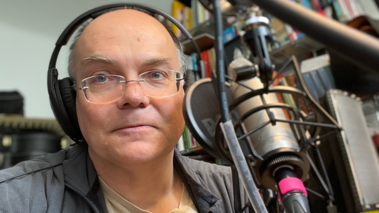 Fotografie von Stephan Ozsváth mit Kopfhörer vor einem großen Mikrofon in seinem Büro Fotografie von Stephan Ozsváth mit Kopfhörer vor einem großen Mikrofon in seinem Büro