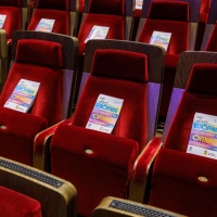 Red velvet seats with the flyers for the opening of the Leipzig Book Fair 2025 placed on them
