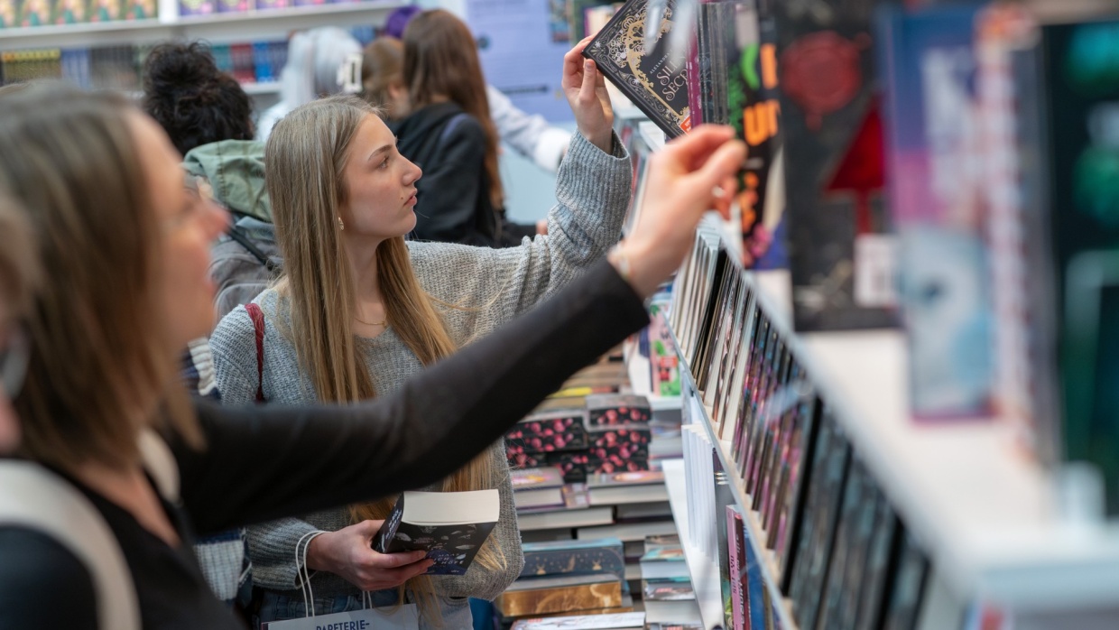 Woman takes a book from a shelf at the Leipzig Book Fair 2025