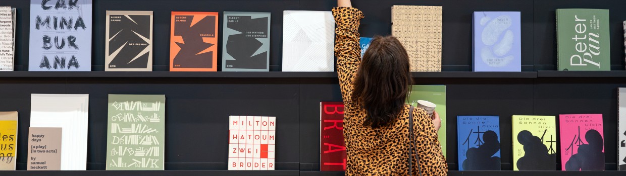A visitor to the Leipzig Book Fair in 2025 takes a book from a wall displaying books