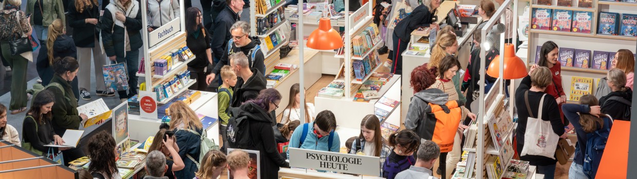 Impression of the exhibition area at the Leipzig Book Fair 2025 with exhibition stands and many visitors.