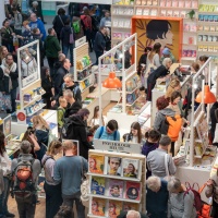 Impression of the exhibition area at the Leipzig Book Fair 2025 with exhibition stands and many visitors.