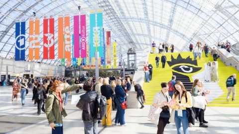 A bustling glass hall during Leipzig Book Fair, filled with cheerful visitors