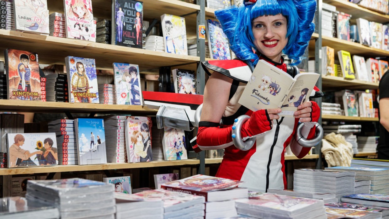 Macoco reading Manga at a trade fair stand at Manga Comic Con 2026